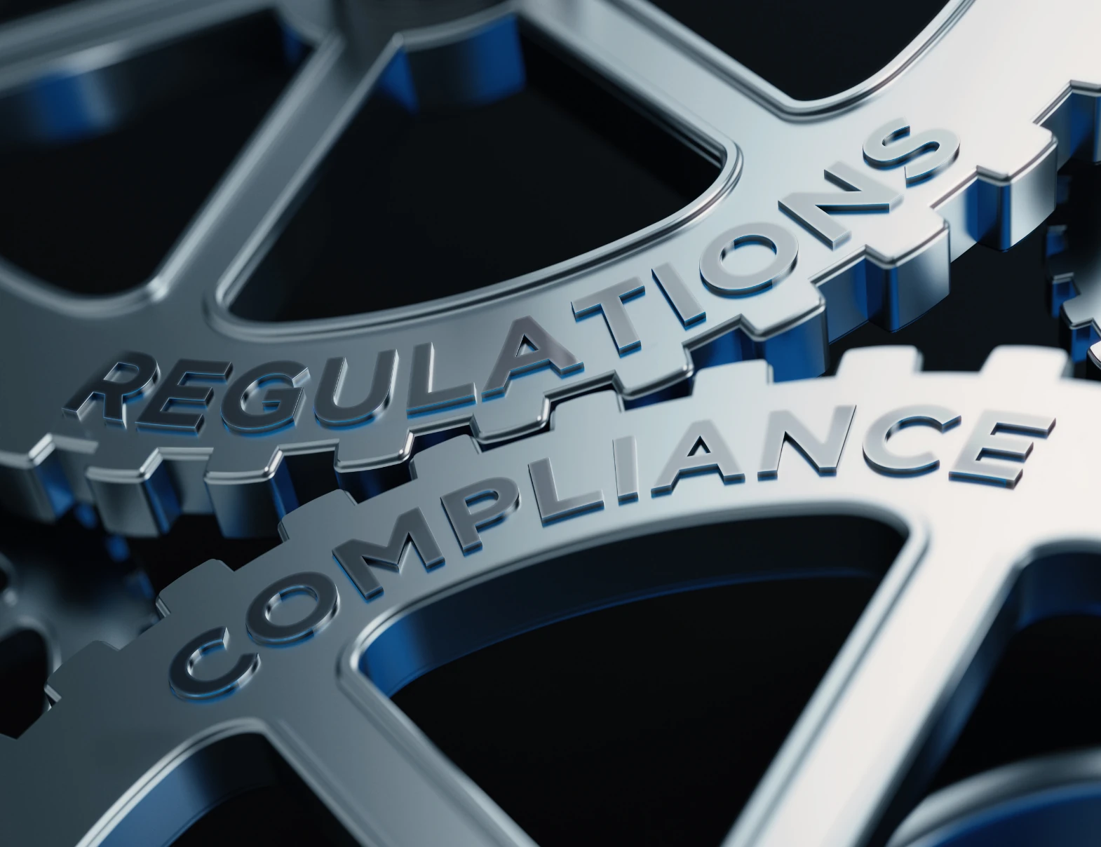 Interlocking metal gears engraved with the words Regulations and Compliance